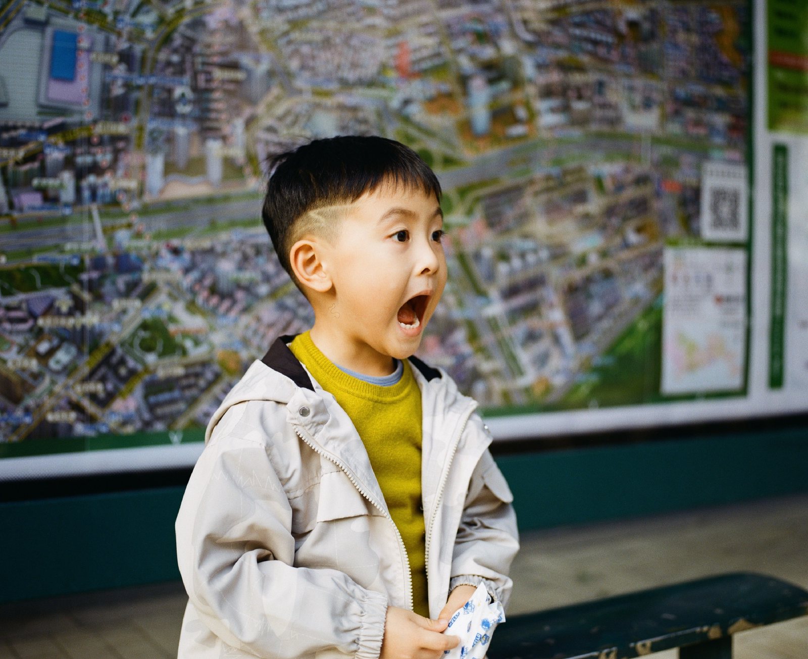 儿子站在一张城市航拍地图前，张大嘴