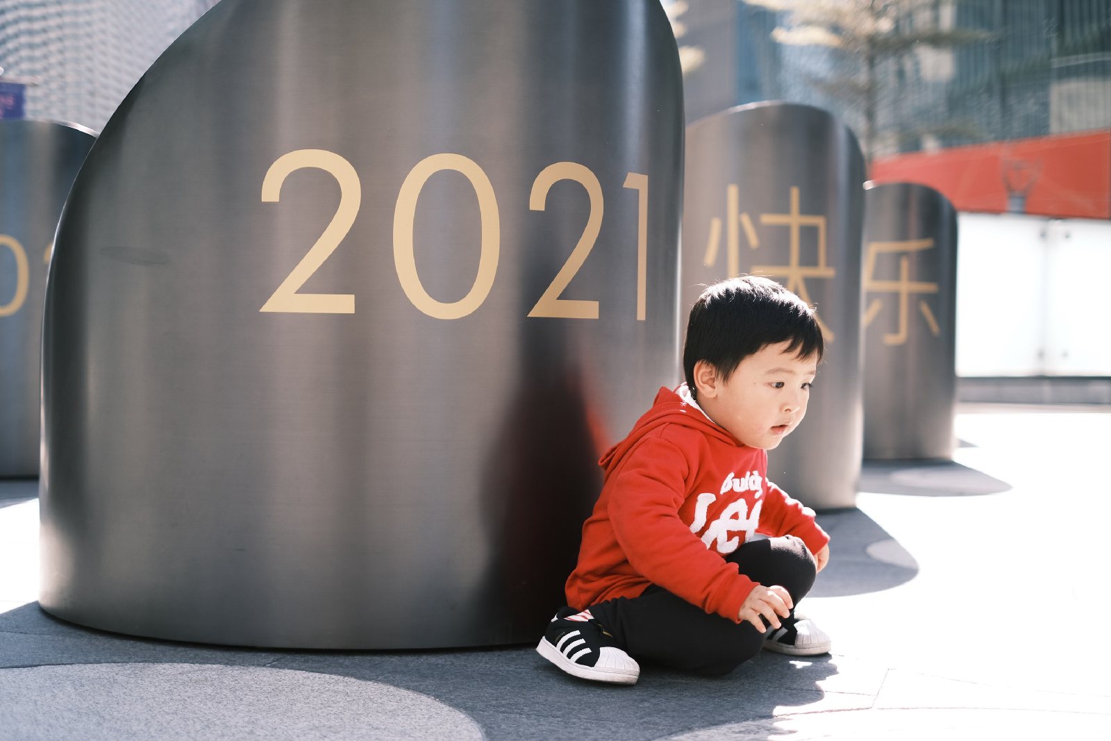 儿子蹲在写着 2021 的柱子旁