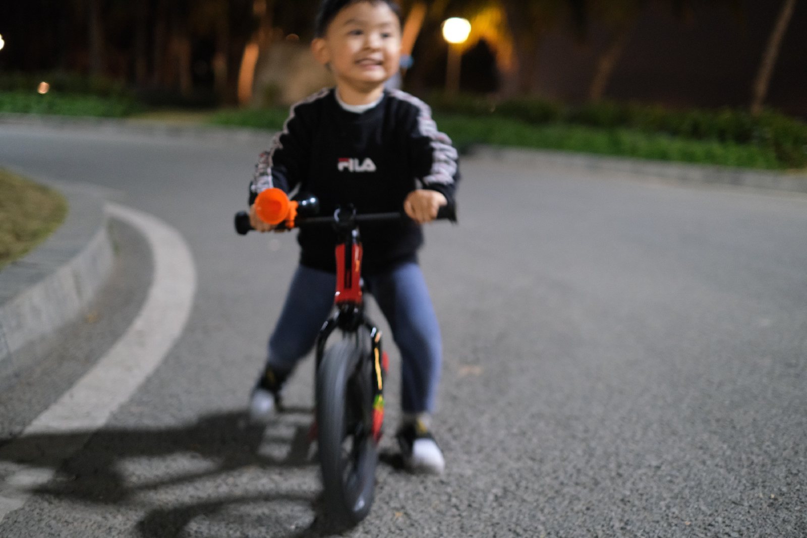 夜里路灯下，儿子骑滑步车冲过来