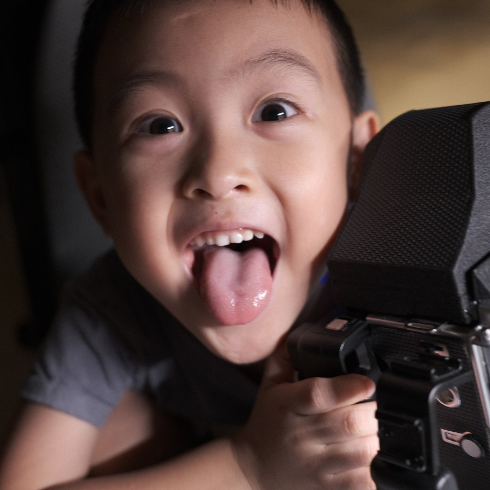 儿子抱着 Mamiya C220，冲镜头吐舌头