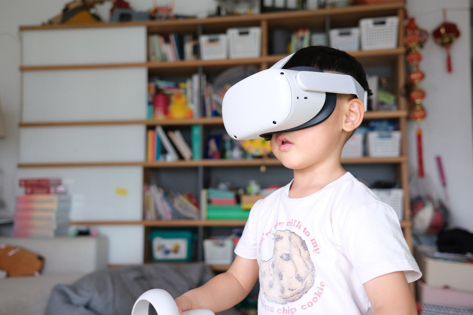 儿子戴着 VR 头显站在书架前