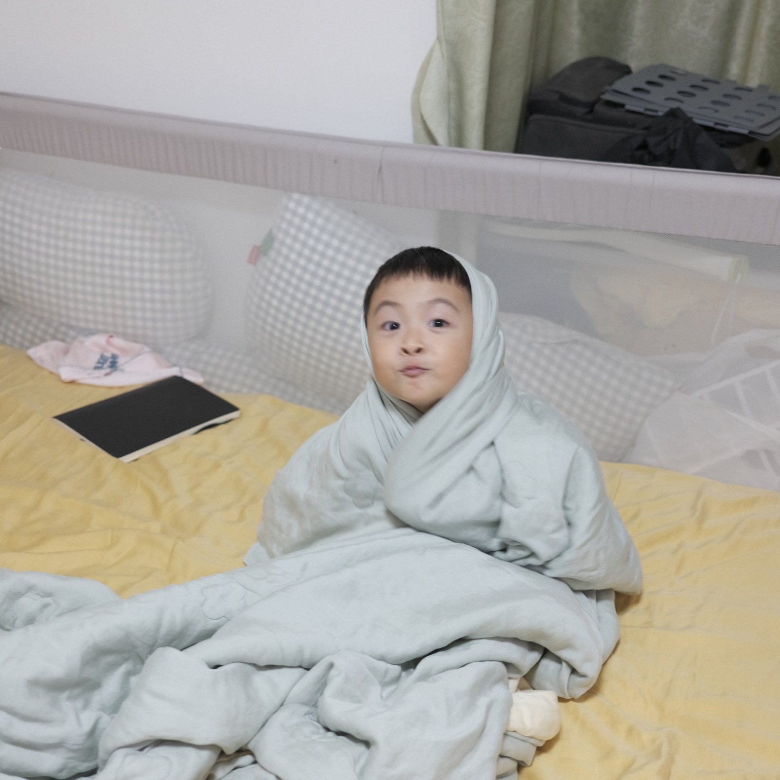 儿子裹在被子里坐在床上
