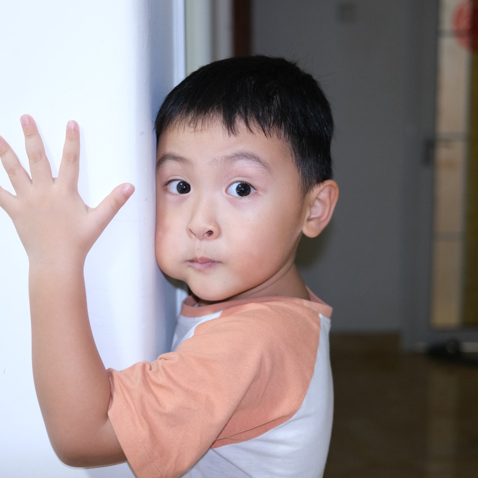儿子一手扶着墙，歪头看镜头