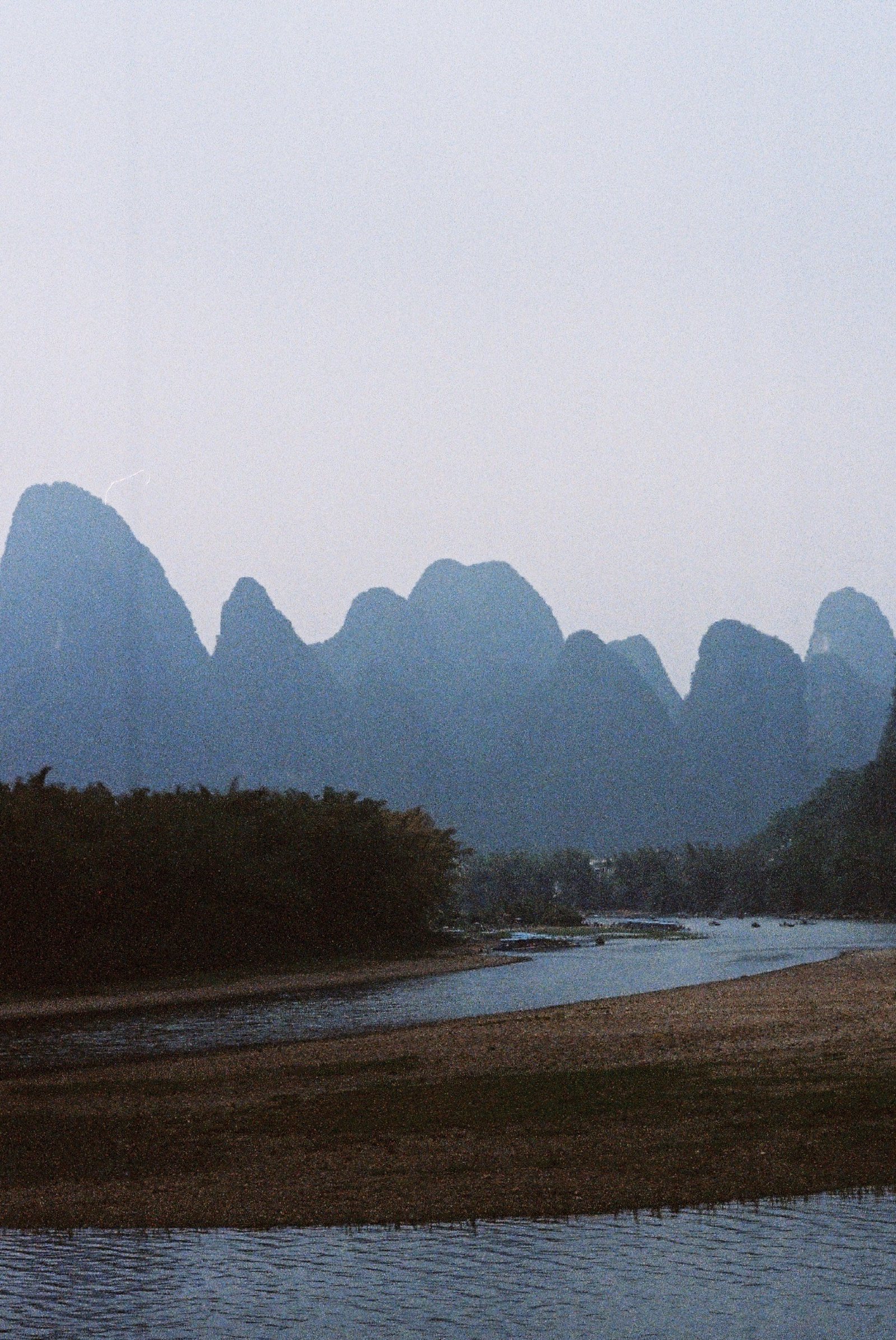 竖拍江边的山，前景是沙滩