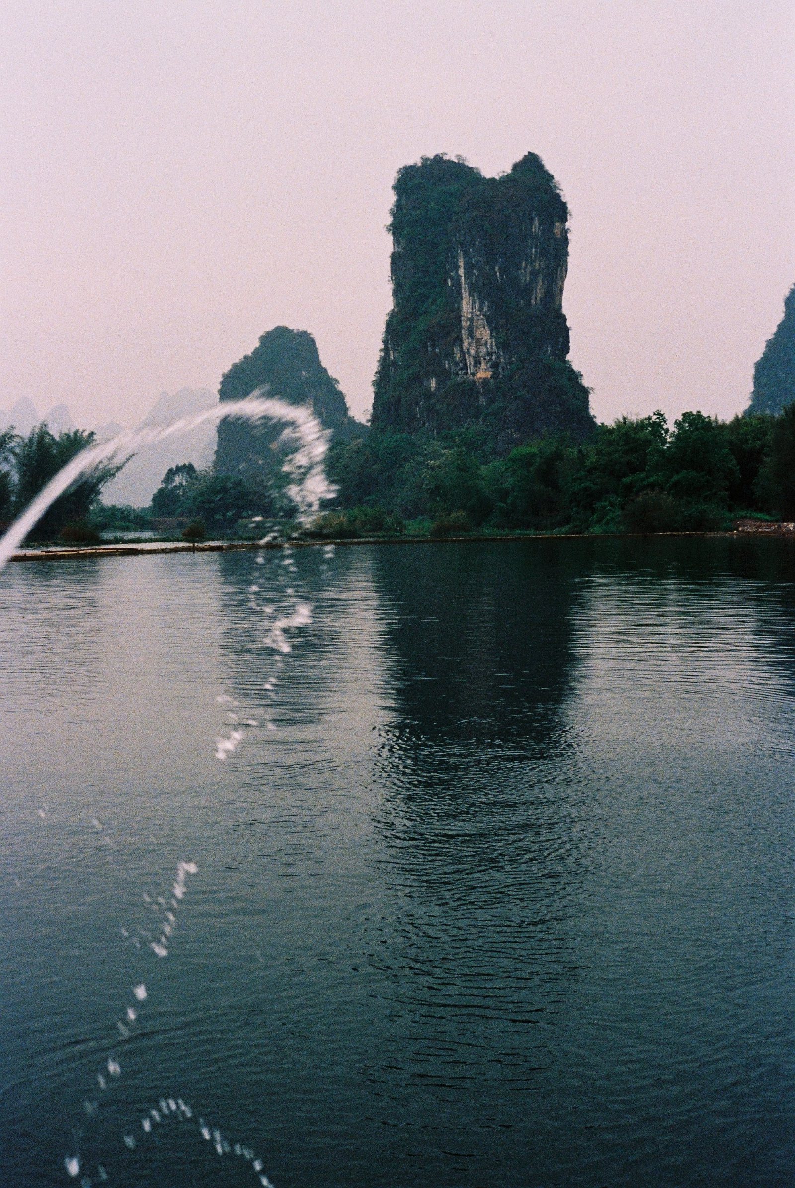 傍晚江上的喷泉，后面是一座尖山