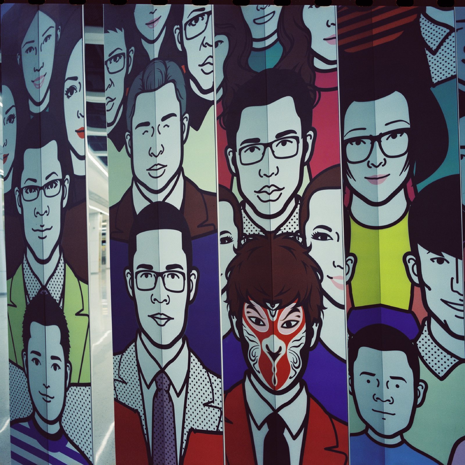 地铁站的壁画，一排排卡通人脸，中间一张是京剧脸谱