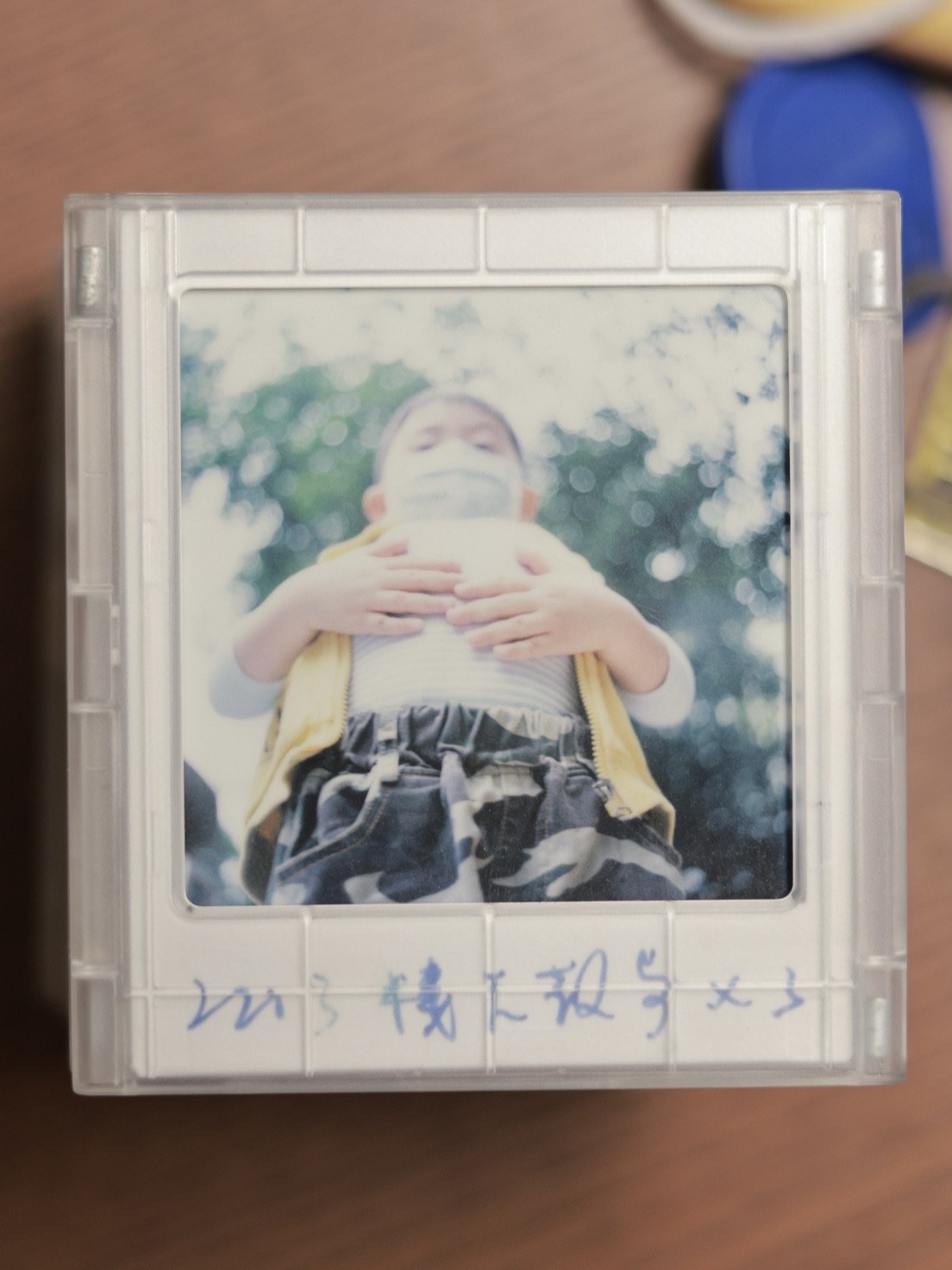 树下，一个孩子举着手挡住脸