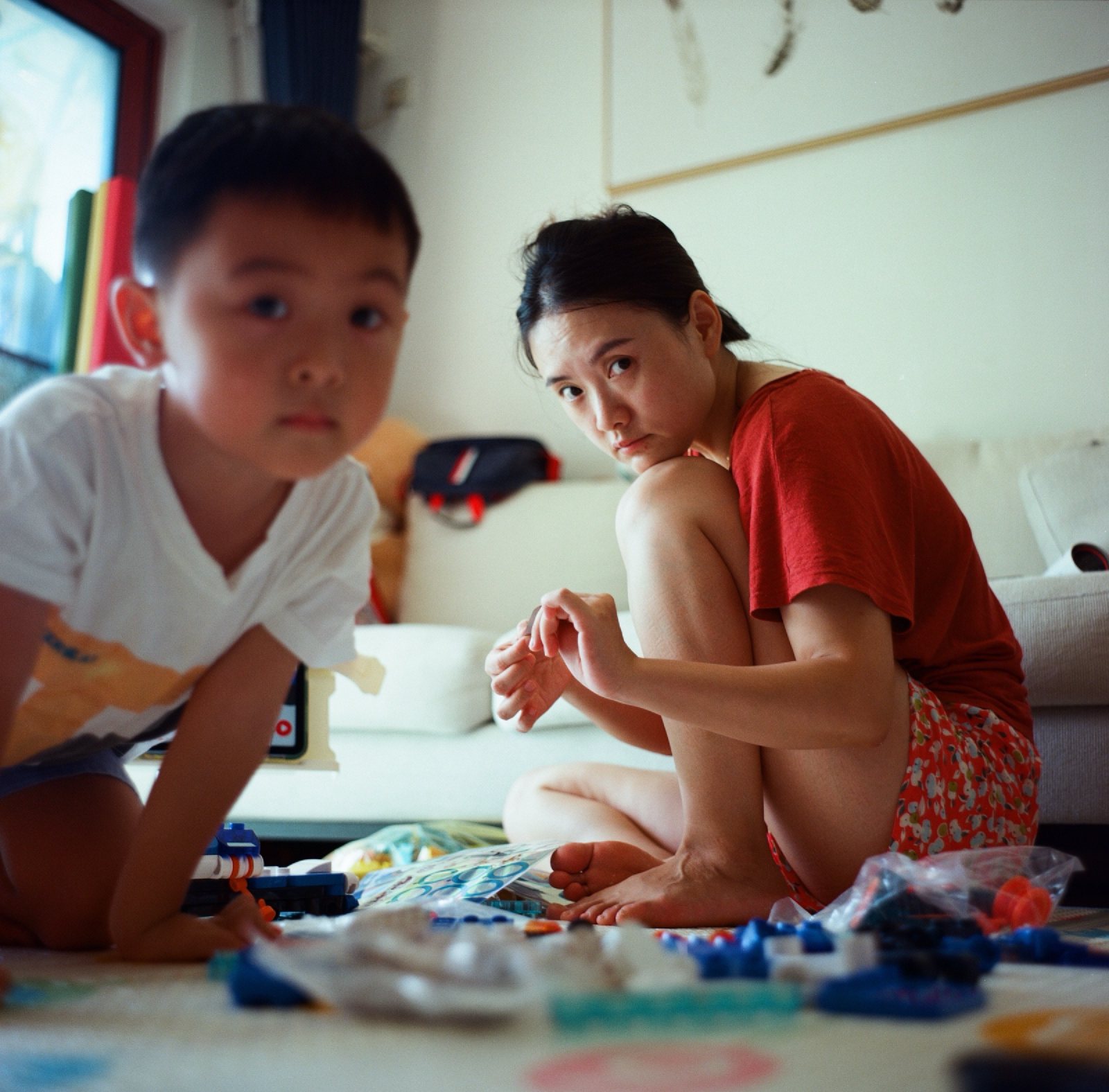 儿子和妈妈一起抬头看镜头，面前一地积木
