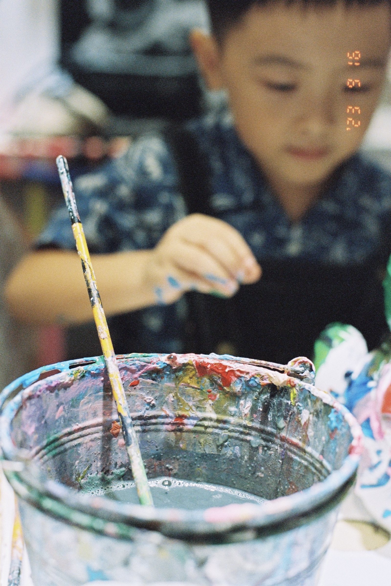 儿子拿着画笔,前景是涮笔的水桶,右上角印着 '23 9 16