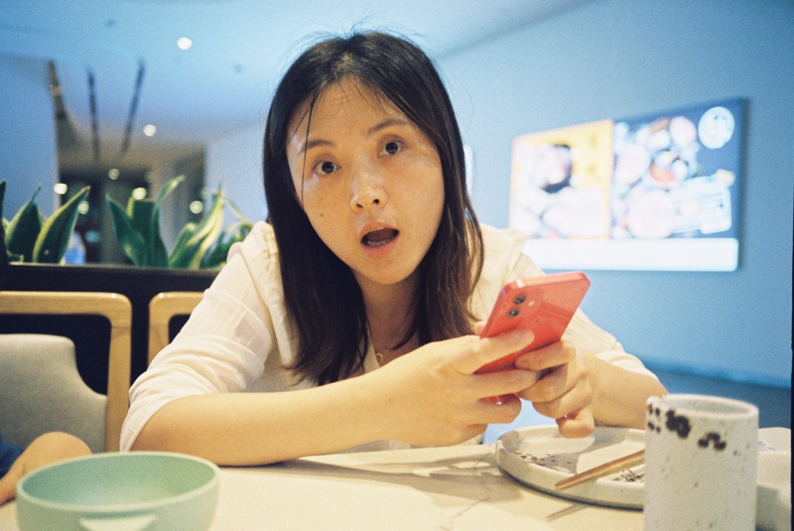 餐厅里妈妈拿着手机张嘴看镜头