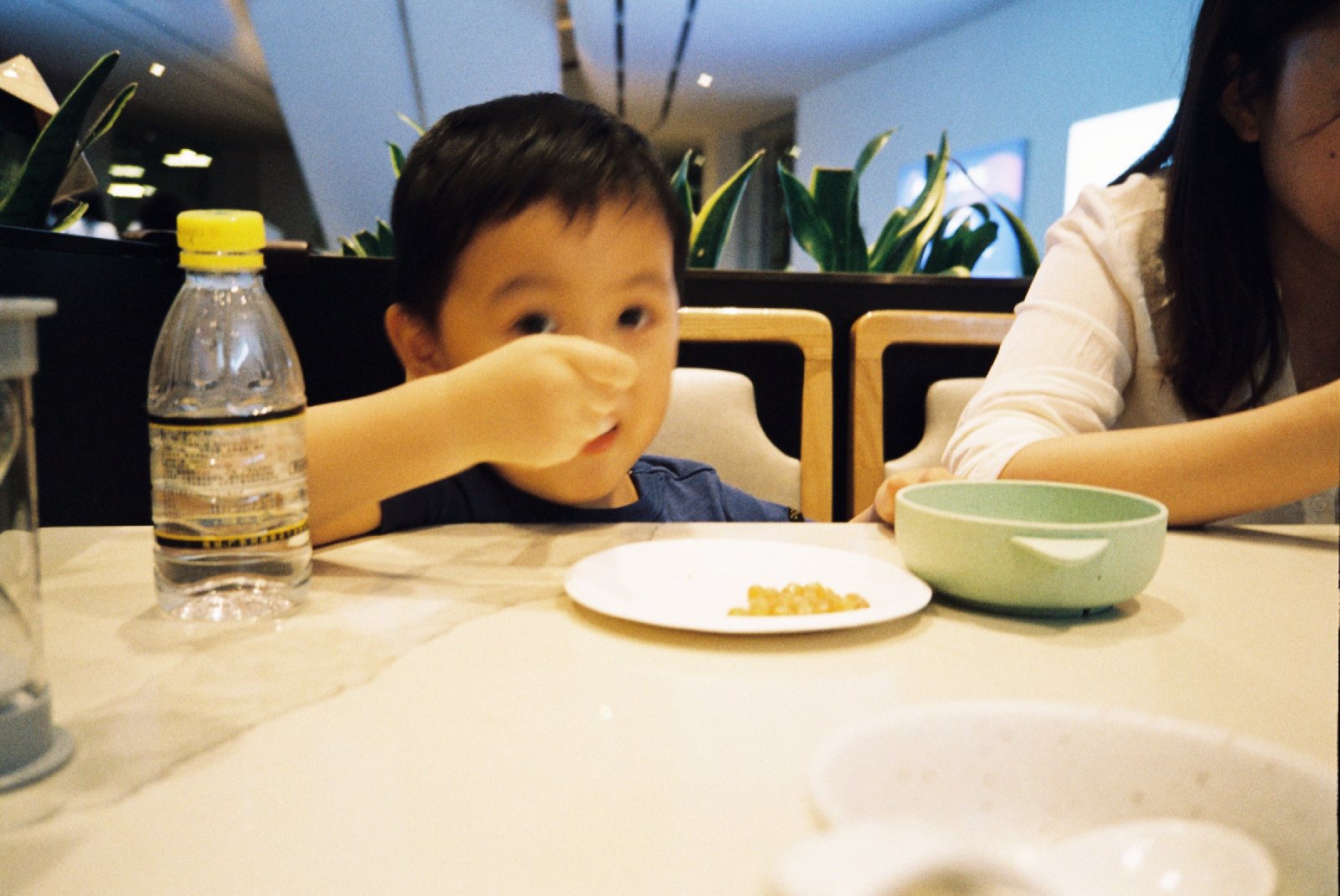 餐桌边儿子往嘴里塞食物，旁边是妈妈