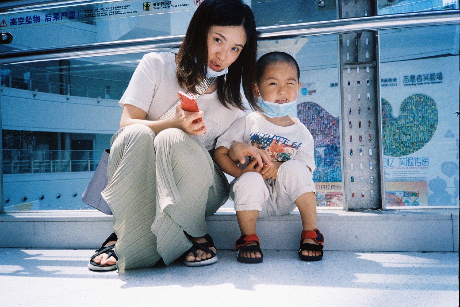 妈妈和儿子戴着口罩坐在商场台阶上