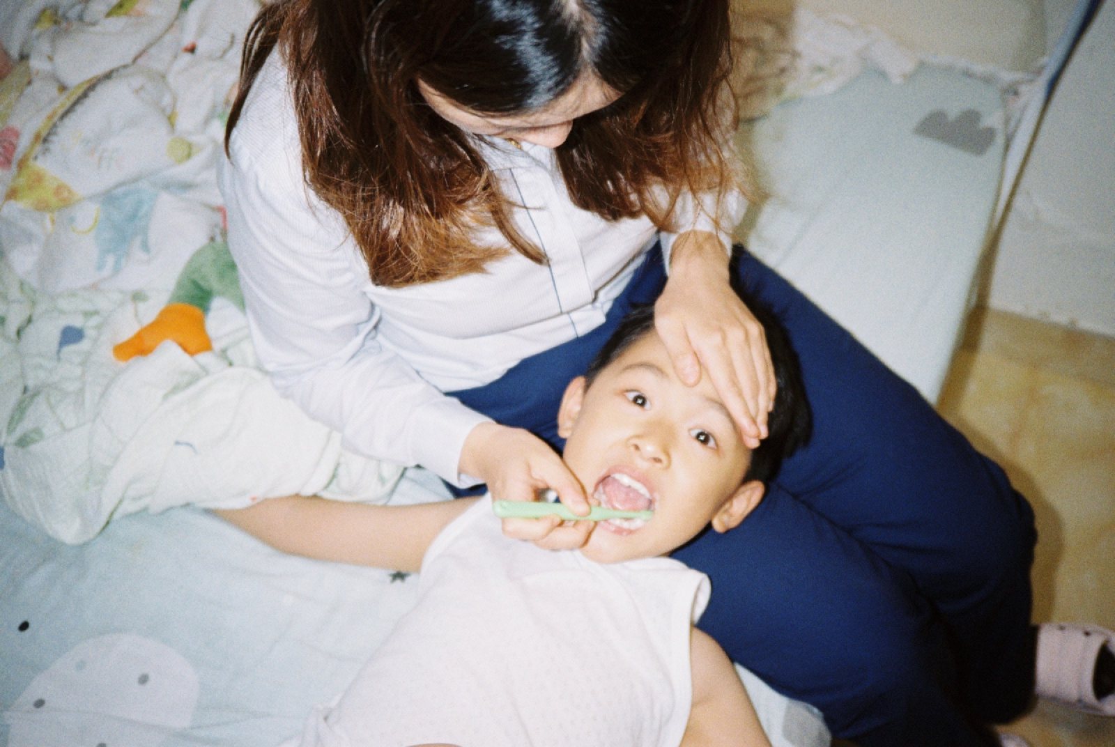 妈妈让儿子躺在腿上刷牙
