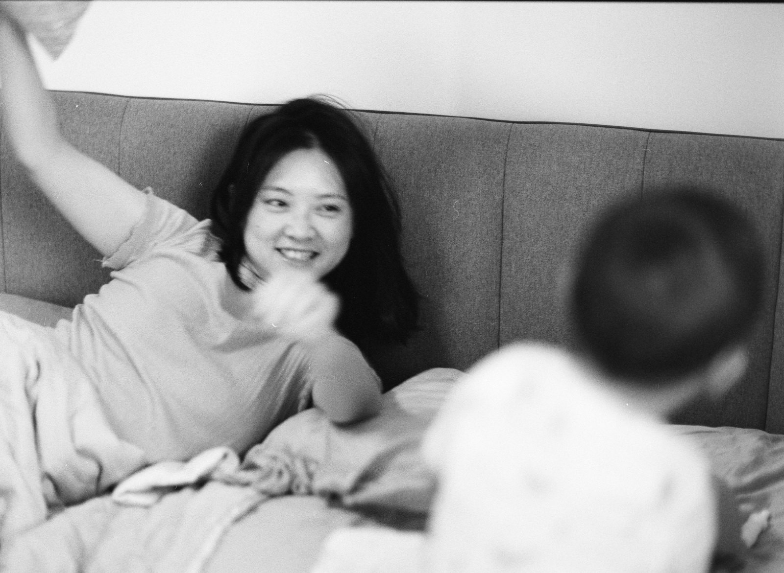 黑白，妈妈靠在床头挥手笑，儿子背对镜头