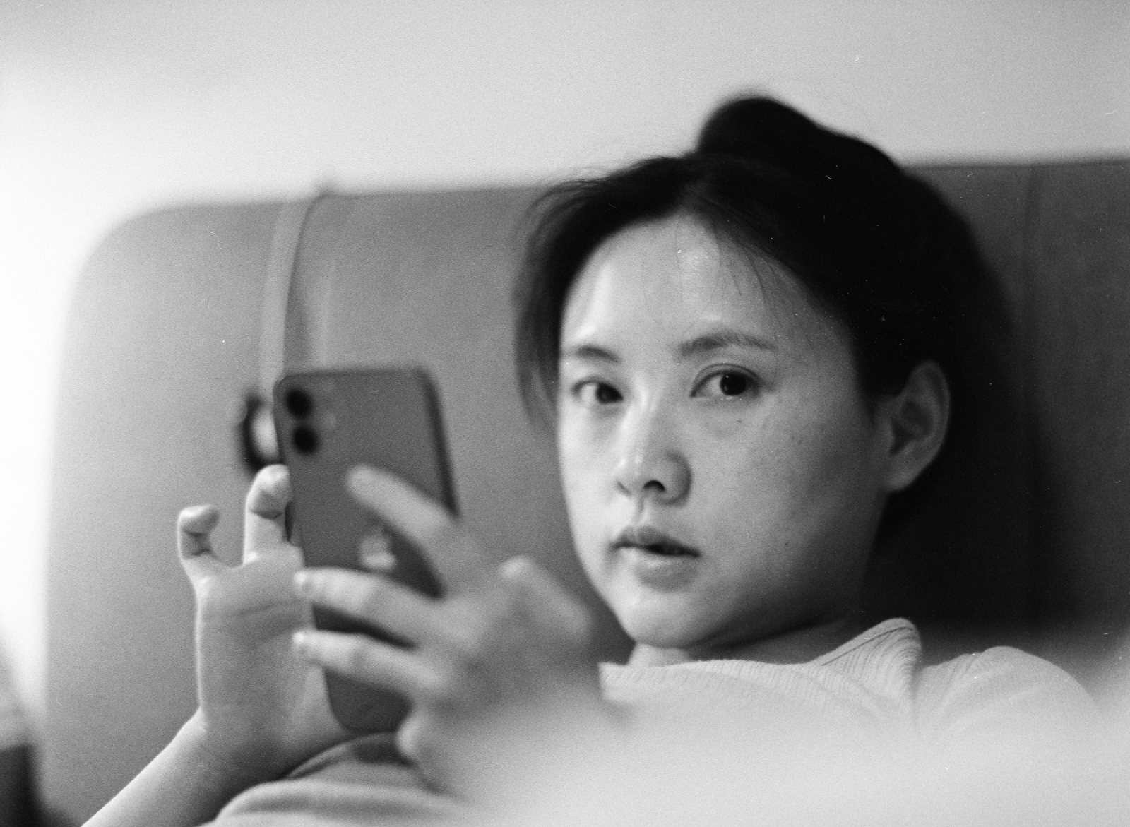 黑白，妈妈拿着手机抬眼看镜头