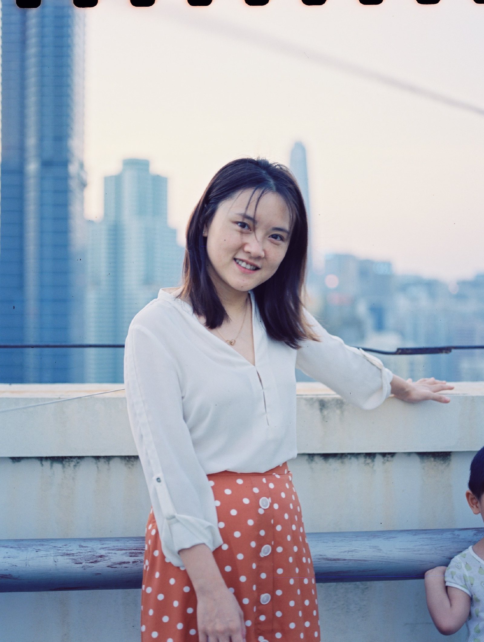 妈妈扶着天台栏杆站着，背后是城市天际线